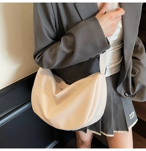 Close-up of cream white crescent bag showing pebbled leather texture and minimalist design