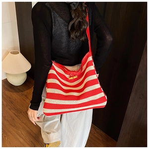 Detail of red striped knit tote bag with smooth leather strap and wooden horn buckle