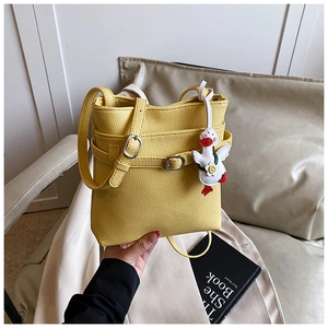 Détail d'un sac seau jaune à motif litchi avec une breloque canard blanc mignonne