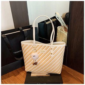 Détail du sac cabas tissé avec rayures jaunes et ses longues anses en cuir blanc