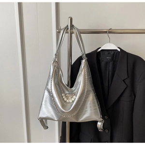 Silberne Metallic-Hobo-Tasche mit Perlenbogen und Ketten auf schwarzem Blazer