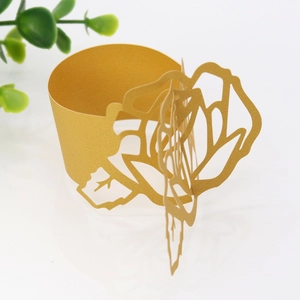 Detailed view of laser-cut gold paper napkin ring with a hollow rose flower design