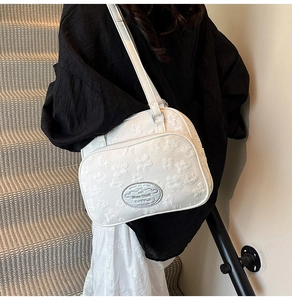 Détail du sac à bandoulière blanc avec motifs floraux gaufrés et plaque en métal