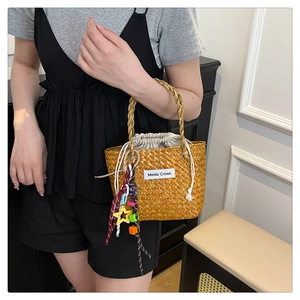 Detail of hand-woven straw tote bag with star charm and drawstring inner liner