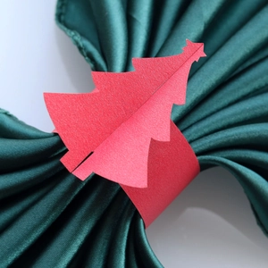 Gros plan d'un rond de serviette en papier rouge en forme de sapin sur du satin