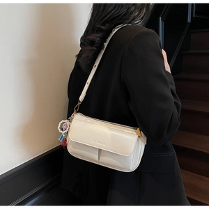 Detail of white leather pillow bag with pearl charm and embossed logo on strap