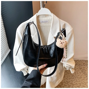 Detail of black faux leather hobo bag featuring crocodile pattern and cute bear charm