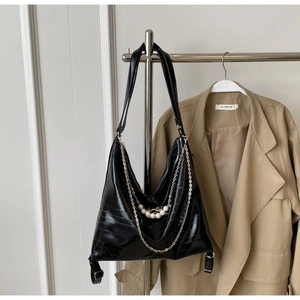Detail der schwarzen Hobo-Tasche mit Krokostruktur, Silberkette und Perlen-Deko