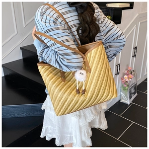 Gros plan du sac fourre-tout tissé avec bandoulière en cuir et pendentif peluche