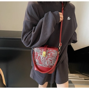 Detail of burgundy bucket bag with white traditional embroidery and gold clasp