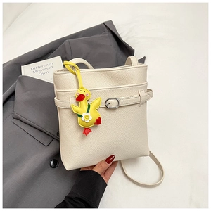 Détail du sac seau en cuir crème avec une breloque canard jaune décorative