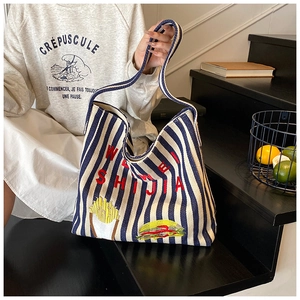 Détail du sac cabas en toile rayé bleu et blanc avec broderie rouge et écussons gourmands