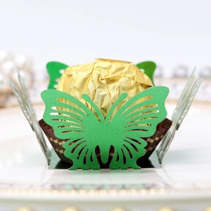 Macro detail of laser-cut green butterfly candy holder with golden chocolate on white plate