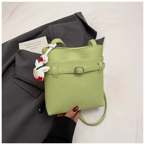 Détail du sac seau vert en cuir grainé avec boucle décorative et charm de canard mignon