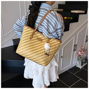 Détail du cabas tissé avec motif à rayures, anses en cuir marron et breloque peluche