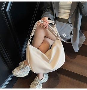 Close-up of beige lychee grain leather underarm bag with adjustable strap and zipper
