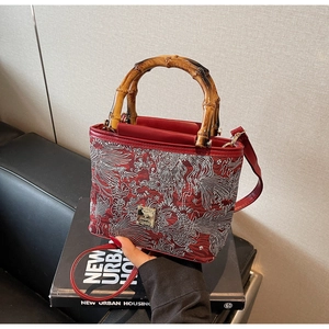 Detail of red leather bucket bag with Chinese embroidery and vintage bamboo handle