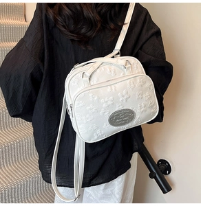 Vue détaillée du sac à bandoulière blanc avec texture florale 3D et logo en métal