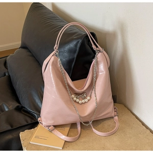 Detail der rosa Lacklederhandtasche mit Silberkette und Anhänger mit weißer Perle