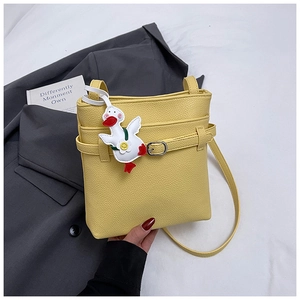 Détail du sac seau en cuir jaune avec charm canard blanc et boucle métallique élégante