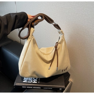 Detailansicht der beigen Canvas-Hobo-Tasche mit braunem Lederriemen und schwarzem TCT-Logo