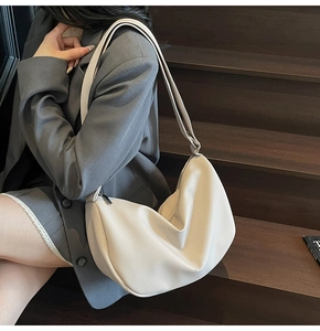 Close-up of beige lychee texture hobo bag with adjustable strap on a leather surface