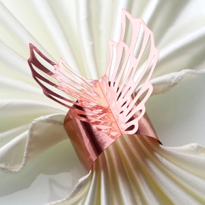 Macro shot of elegant rose gold butterfly napkin ring on a white silk satin background