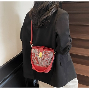 Detail of red bucket bag with traditional embroidery and gold clasp on a model