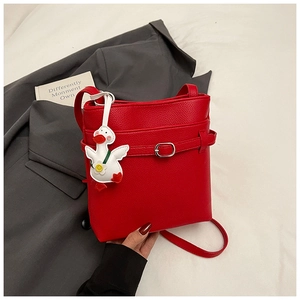 Détail du sac seau rouge à texture litchi avec breloque canard blanc et bandoulière fine