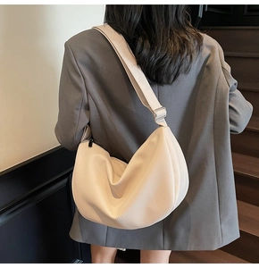 Detail of creamy white crescent leather bag with lychee texture and silver buckle