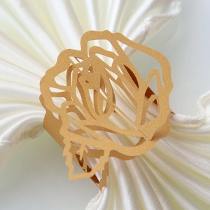 Detail of laser-cut gold rose napkin ring made of pearlescent paper for wedding decor