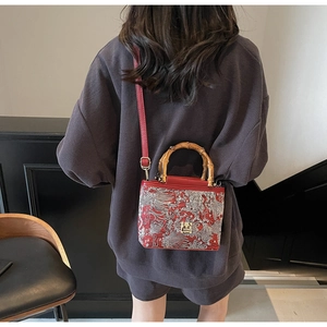 Detail of red Chinese style embroidery handbag with authentic bamboo handle and strap