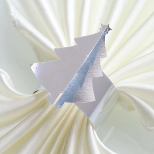 Détail macro d'un rond de serviette en métal sapin de Noël sur satin blanc