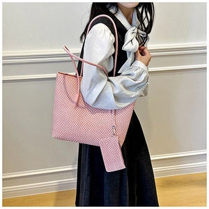 Detail of pink herringbone tote bag and matching mini pouch on a model's shoulder