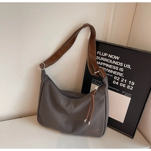 Nahaufnahme der grauen Canvas-Tasche mit braunem Lederriemen, TCT-Stickerei und Quaste