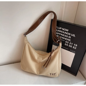 Detailansicht der cremefarbenen Canvas-Tasche mit braunem Lederriemen und TCT-Logo