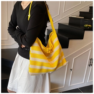 Close-up of yellow and white striped knit tote bag with vintage wooden horn button closure