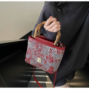 Detail of red Chinese style bucket bag with embroidered koi patterns and bamboo handles