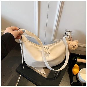 Detail of white crocodile pattern shoulder bag with cute plush bear pendant accessory