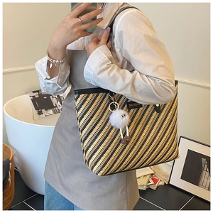 Détail d'un sac cabas tissé à rayures jaunes avec un charmant pompon blanc moelleux