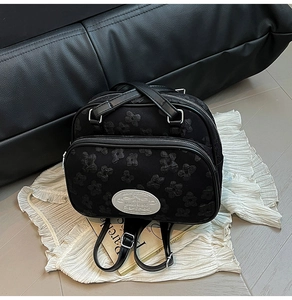 Détail du sac cabas en jacquard noir avec poignées en cuir et fermeture éclair argentée