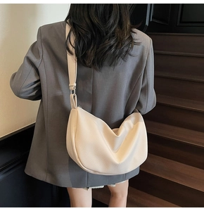 Detailed view of a beige crescent crossbody bag with lychee texture on a model