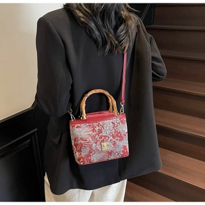 Detail of red embroidered bucket bag with authentic bamboo handle and golden logo