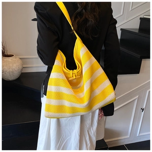 Detail of yellow and white striped knit tote bag featuring a wooden horn button closure