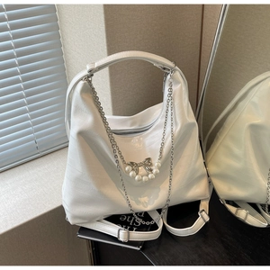 Details einer weißen Hobo-Tasche aus geprägtem Leder mit Perlen- und Schleifenanhänger