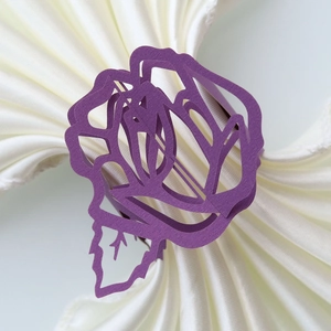 Macro detail of laser-cut purple paper napkin ring with elegant hollow rose and leaf pattern