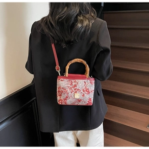 Detail of red embroidery handbag with bamboo handle and elegant silver dragon pattern