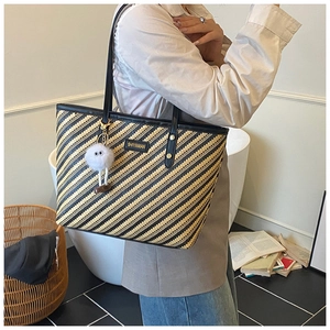 Détail du sac cabas tissé à rayures avec bandoulières en cuir et breloque en peluche