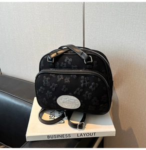 Détail d'un sac à dos noir avec texture florale 3D et plaque métallique Moon Shark argentée