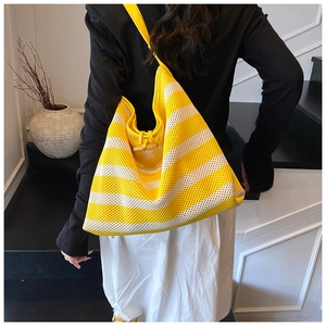 Detail of striped knit tote bag featuring a wooden horn buckle and yellow leather strap